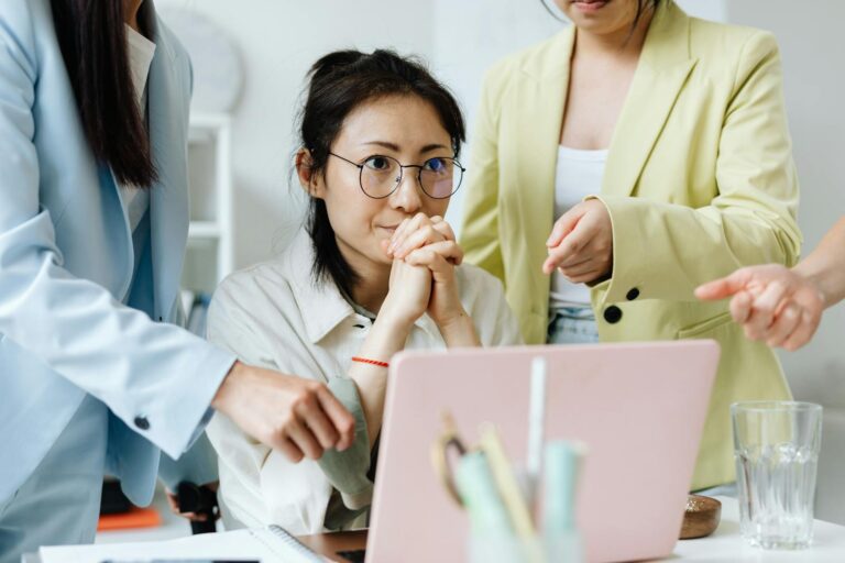 Three businesswomen collaborating on a project in a modern office setting.