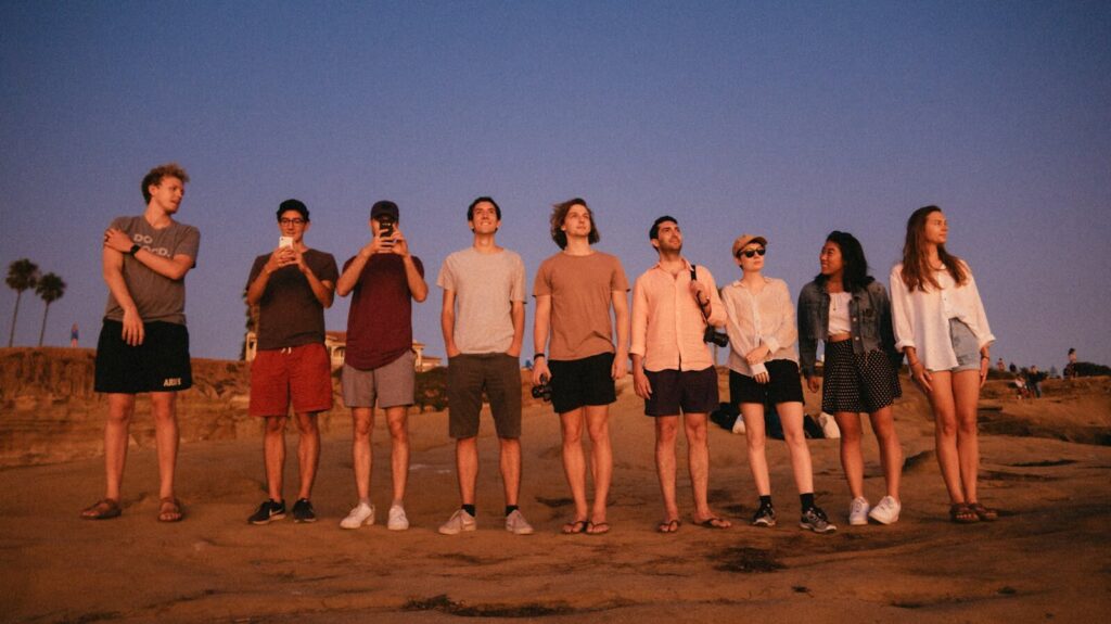 A diverse group of young adults standing together at a beach during sunset. Capturing the essence of friendship.